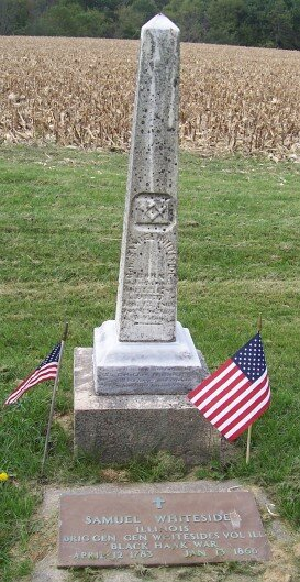 Samuel Whiteside’s weathered obelisk grave marker, with two American flags and a commemorative plaque.